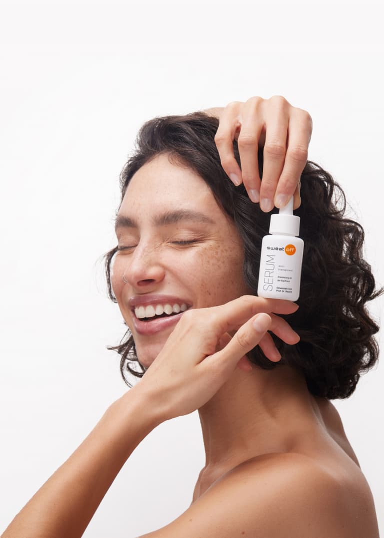 Frau mit dunklen Haaren hält das Serum seitlich vor Ihre Haare