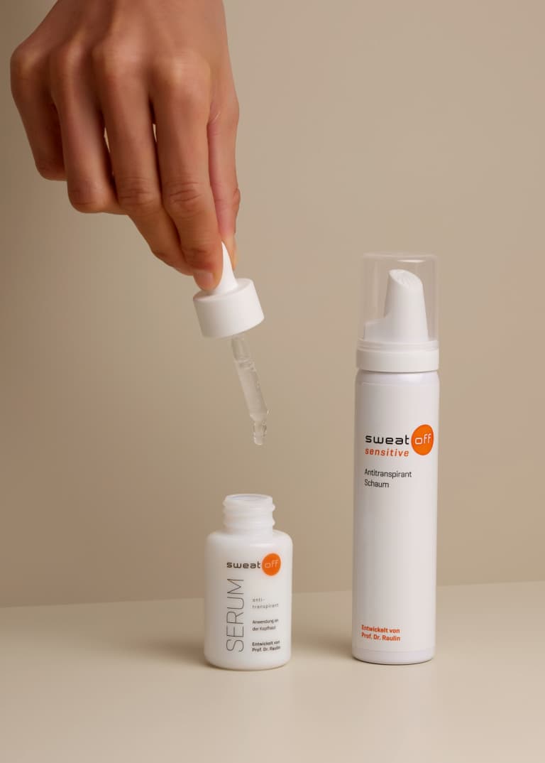 Antitranspirant Serum geöffnet, Pipette wird von einer Hand über das Serum gehalten, daneben steht der Antitranspirant Schaum
