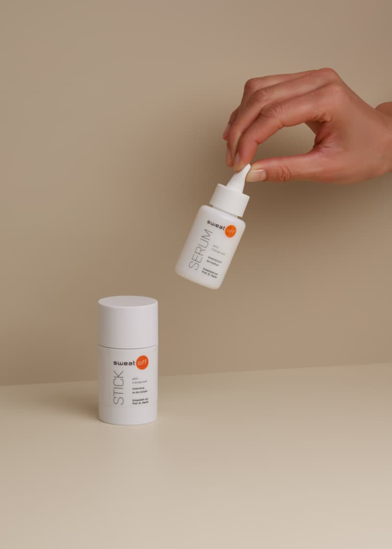 Antitranspirant Stick und Serum, das Serum wird von einer Hand hochgehoben