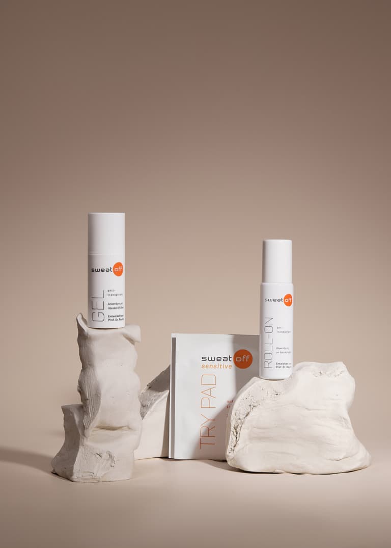 zwei Pads, ein mini Roll-On und ein mini Gel auf Tonskulpturen und beigem Hintergrund